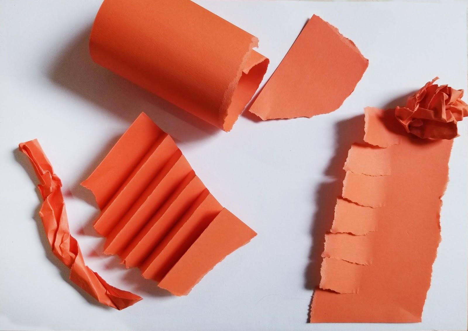 White background with orange strips of paper rolled up and torn and folded