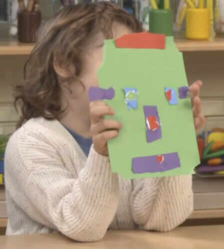 child holding up green mask