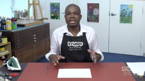 teacher with hands up over a table with a white piece of paper