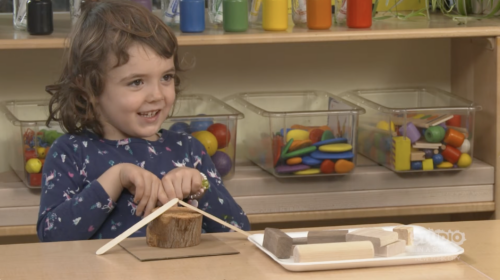 child using wooden objects at a shared desk