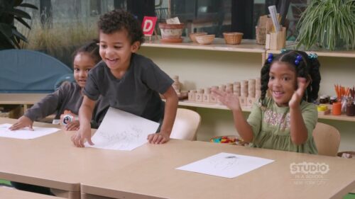 3 children with white paper in front of them on a shared desk